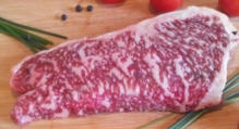 Een mooie gemarmerde wagyu entrecote op een houten plankje met tomaatjes.